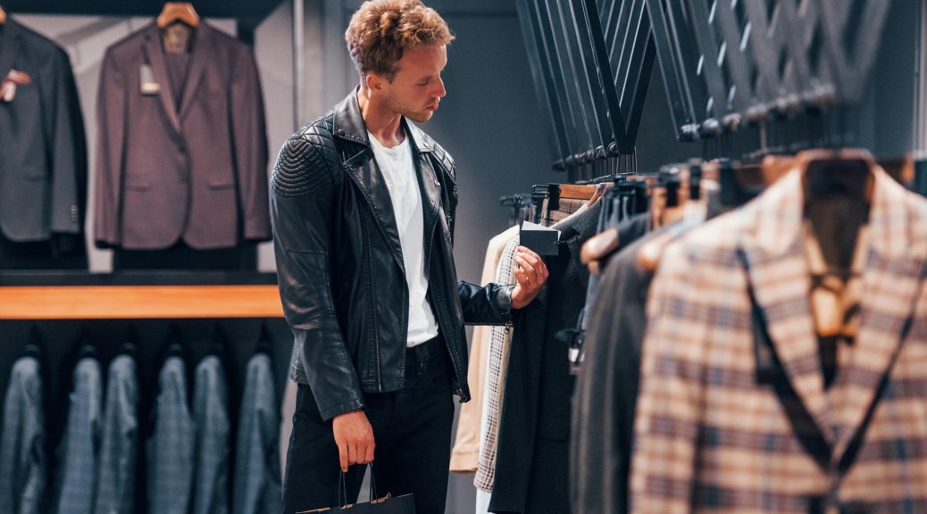 Young guy in modern store with new clothes. Elegant expensive wear for men