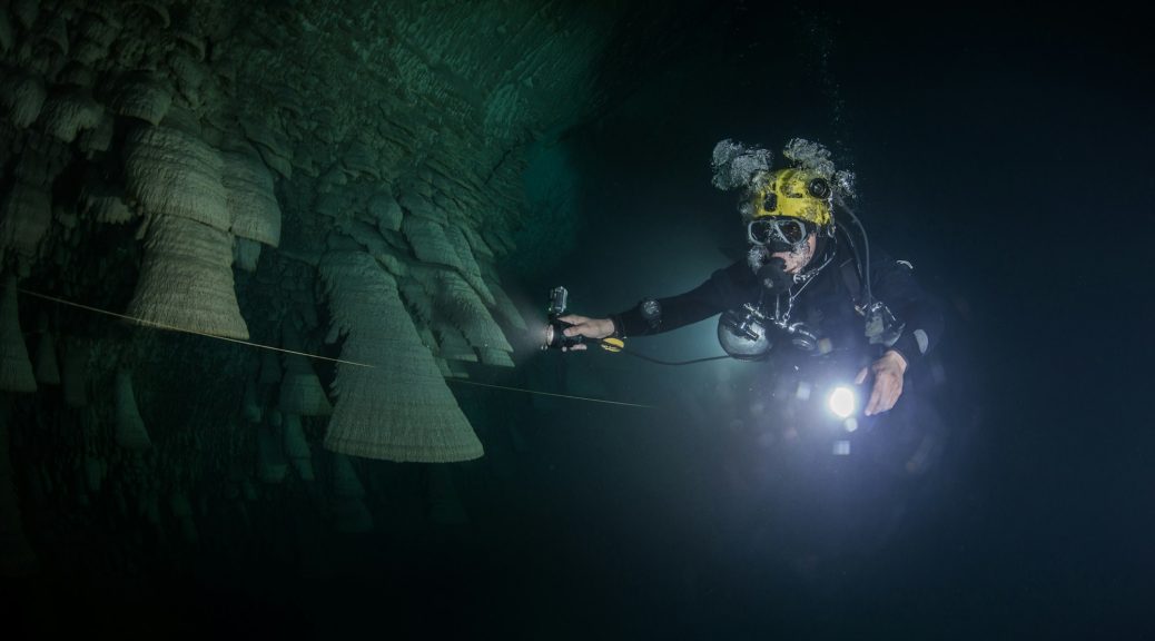 Scuba diver exploring unique natural formations known as "bells" in submerged caves beneath the
